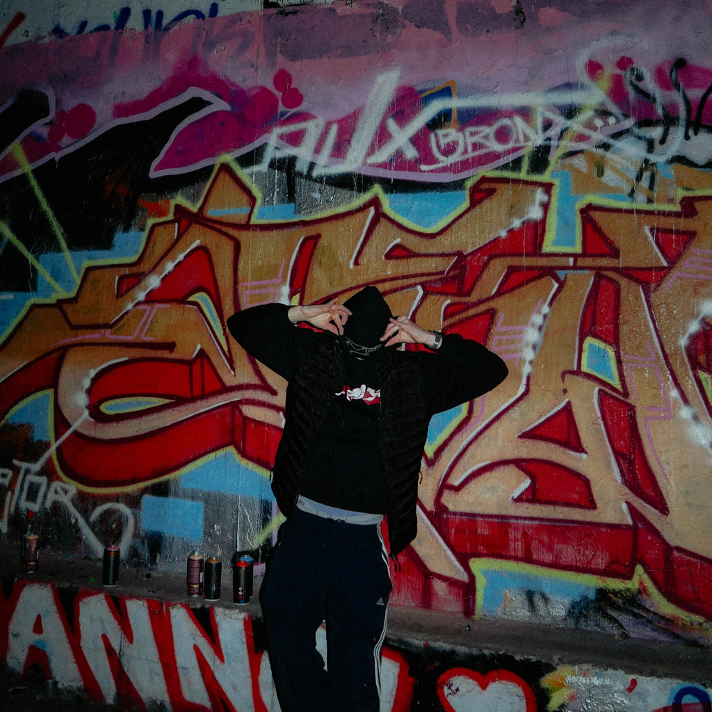 Schwarzer Elektro Hoodie vor Graffiti-Wand getragen – exakt clothing