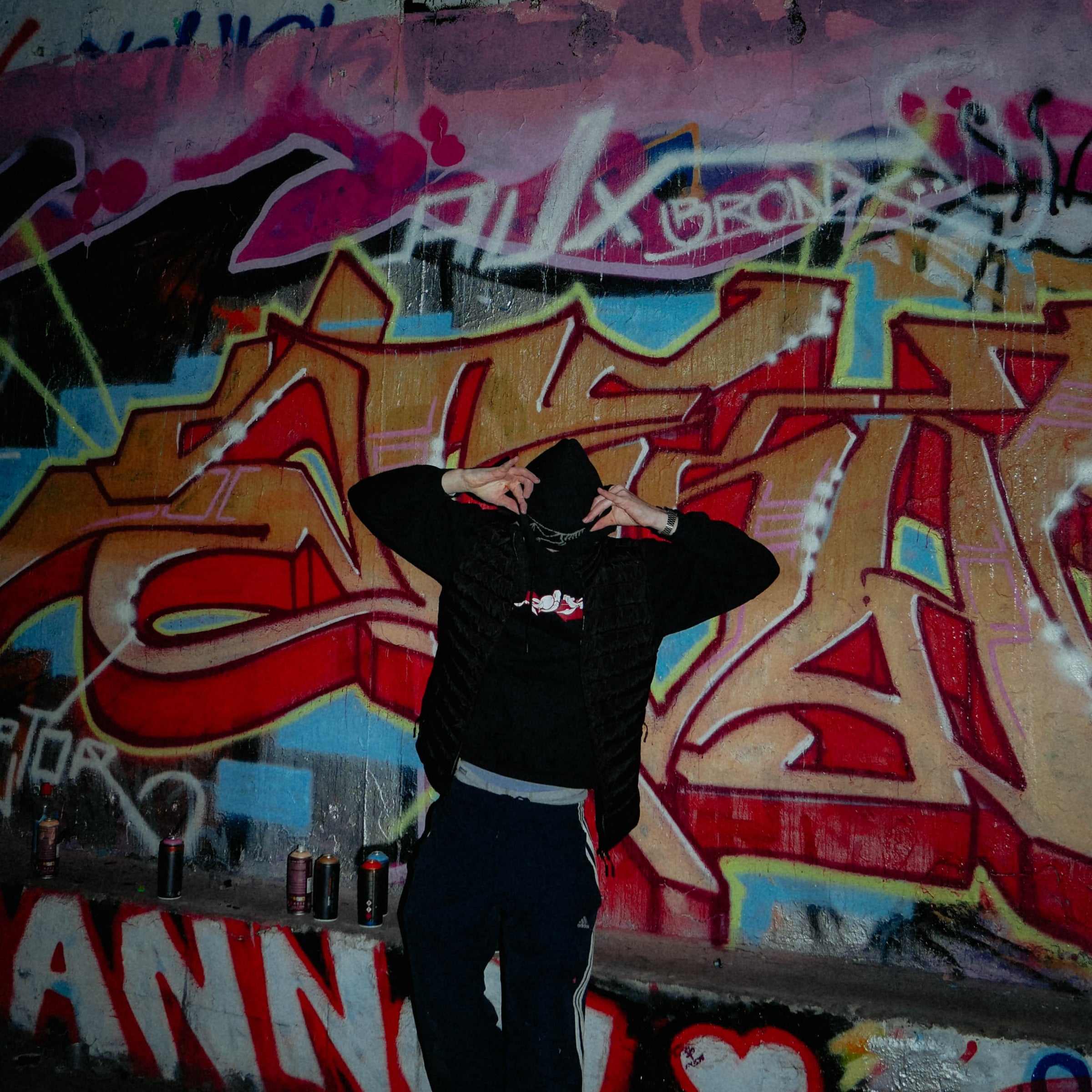 Schwarzer Elektro Hoodie vor Graffiti-Wand getragen – exakt clothing